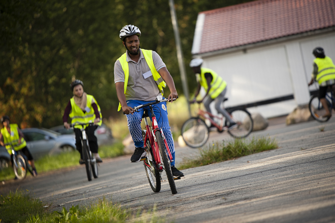 Flera nybörjare i reflexväst som cyklar på asfalt i rund ring.